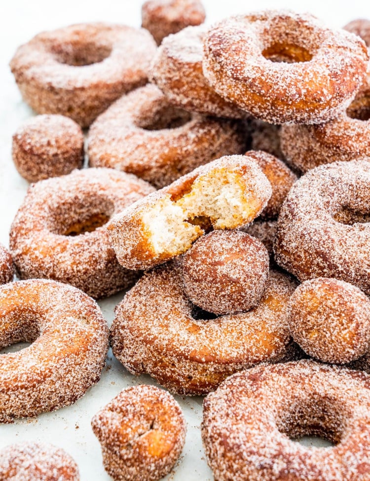a bunch of apple cider donuts stacked on top of each other with a bite taken out of one