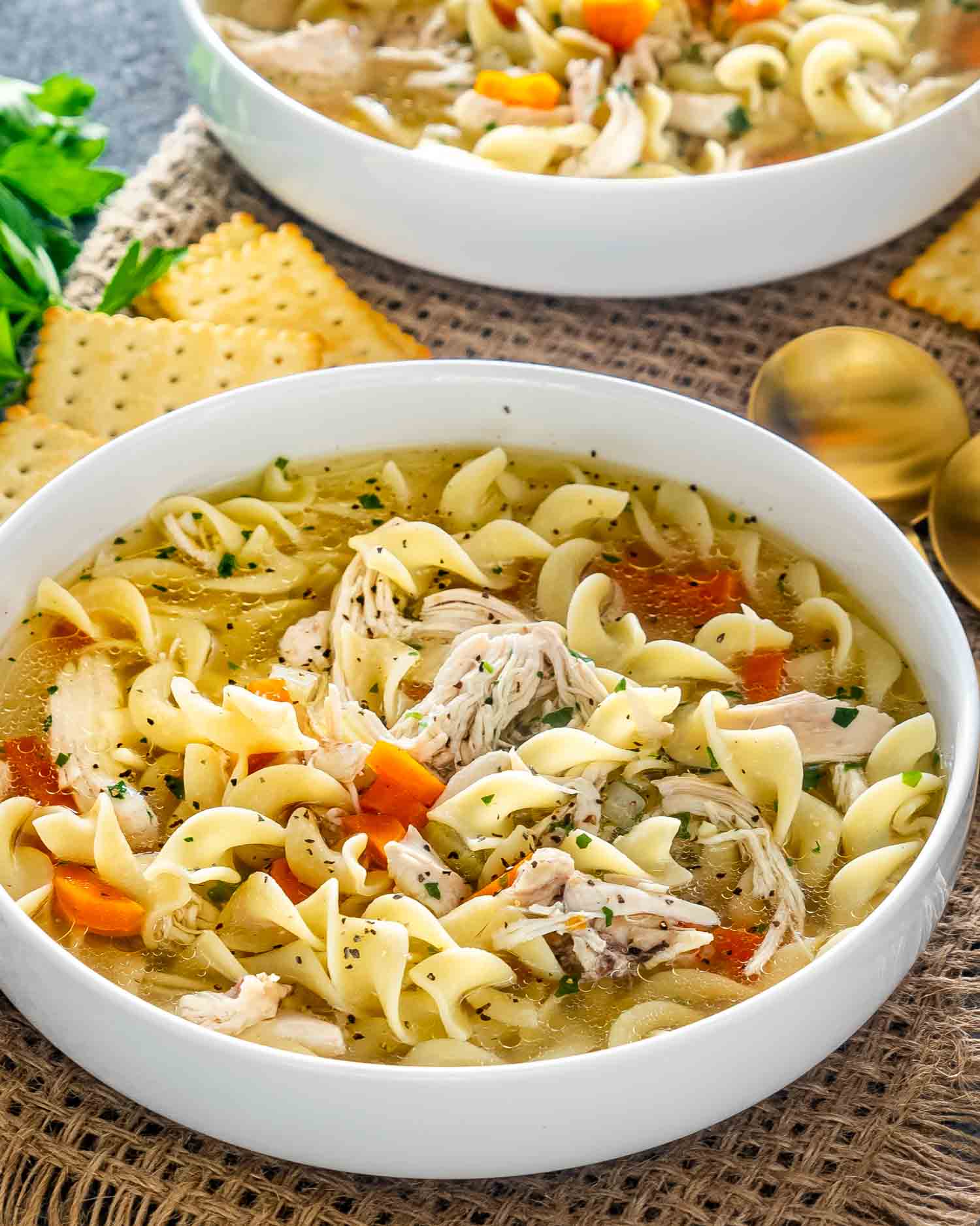 freshly made chicken noodle soup in 2 white bowls.