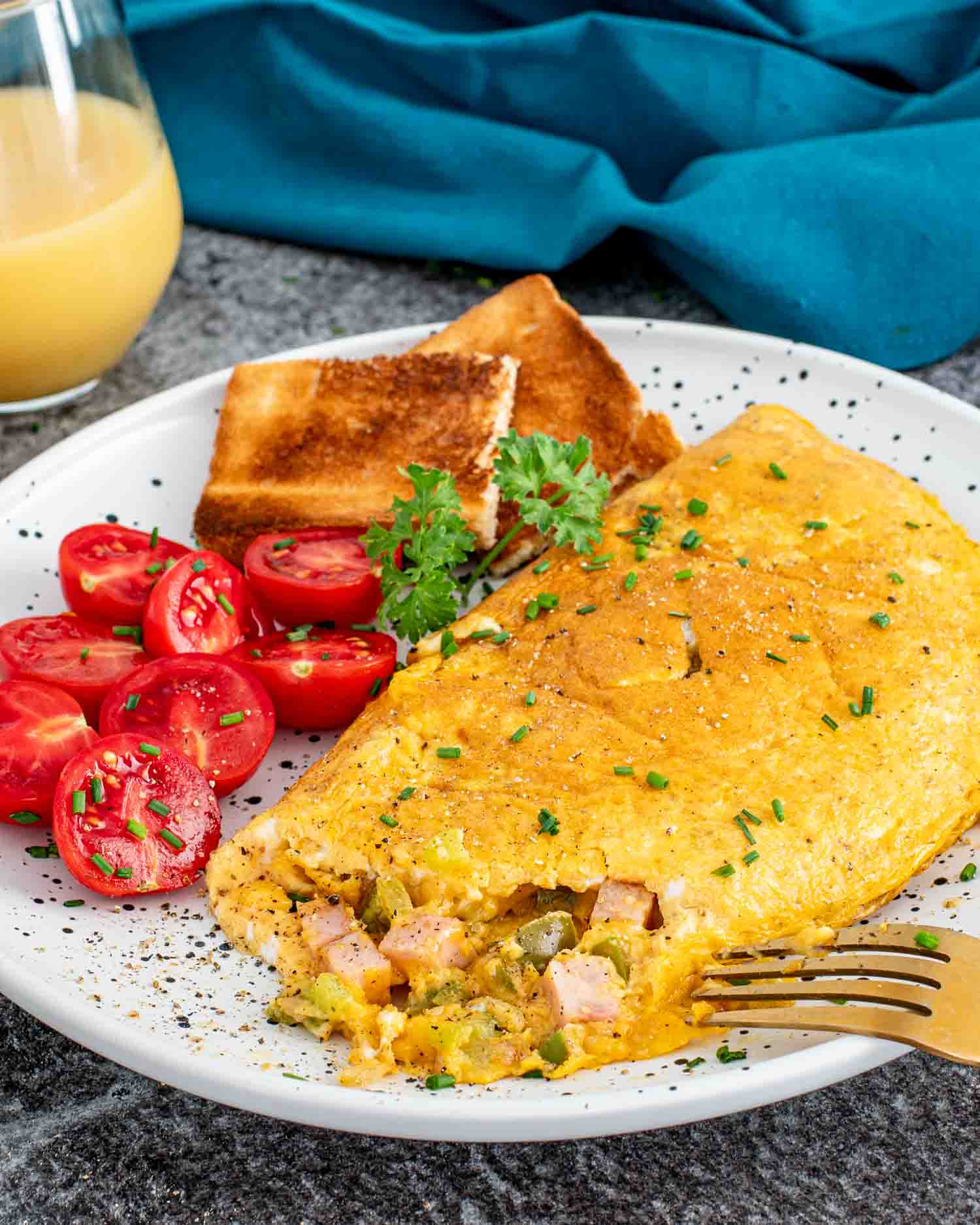 a denver omlette on a plate alongside some cherry tomatoes and toast.