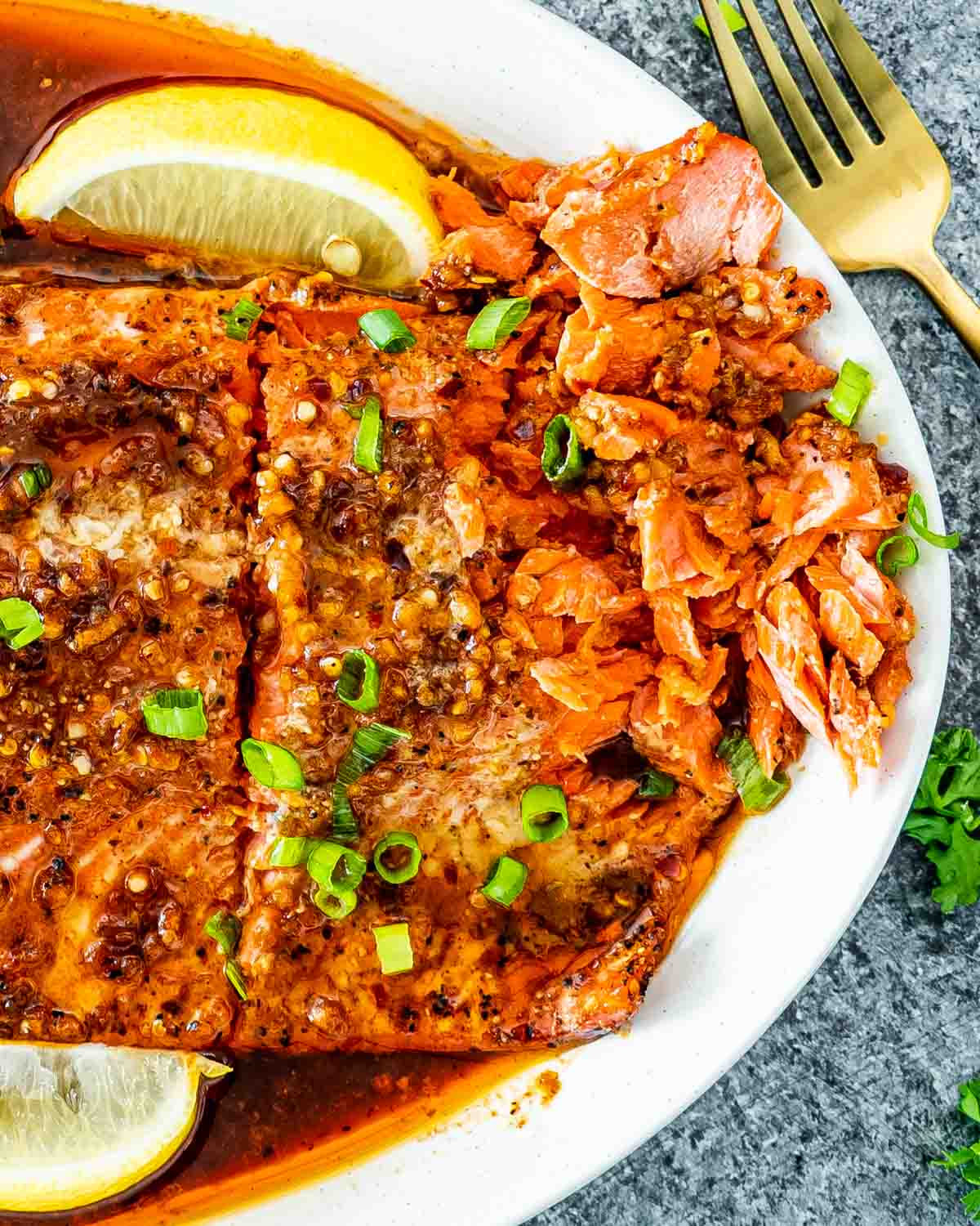 firecracker salmon on a serving platter garnished with lemon wedges and green onions.