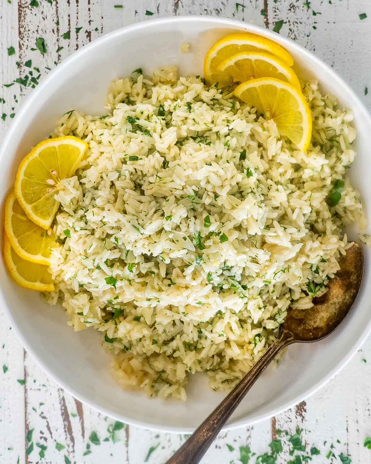 greek rice in a white bowl garnished with lemon slices.