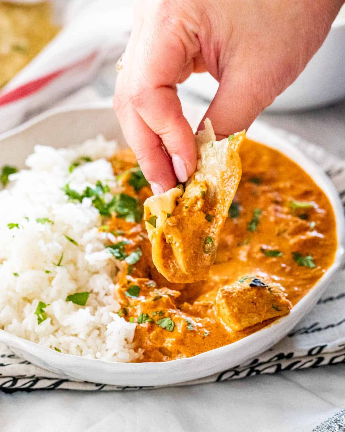 chicken tikka masala in a plate with rice and garnished with cilantro.