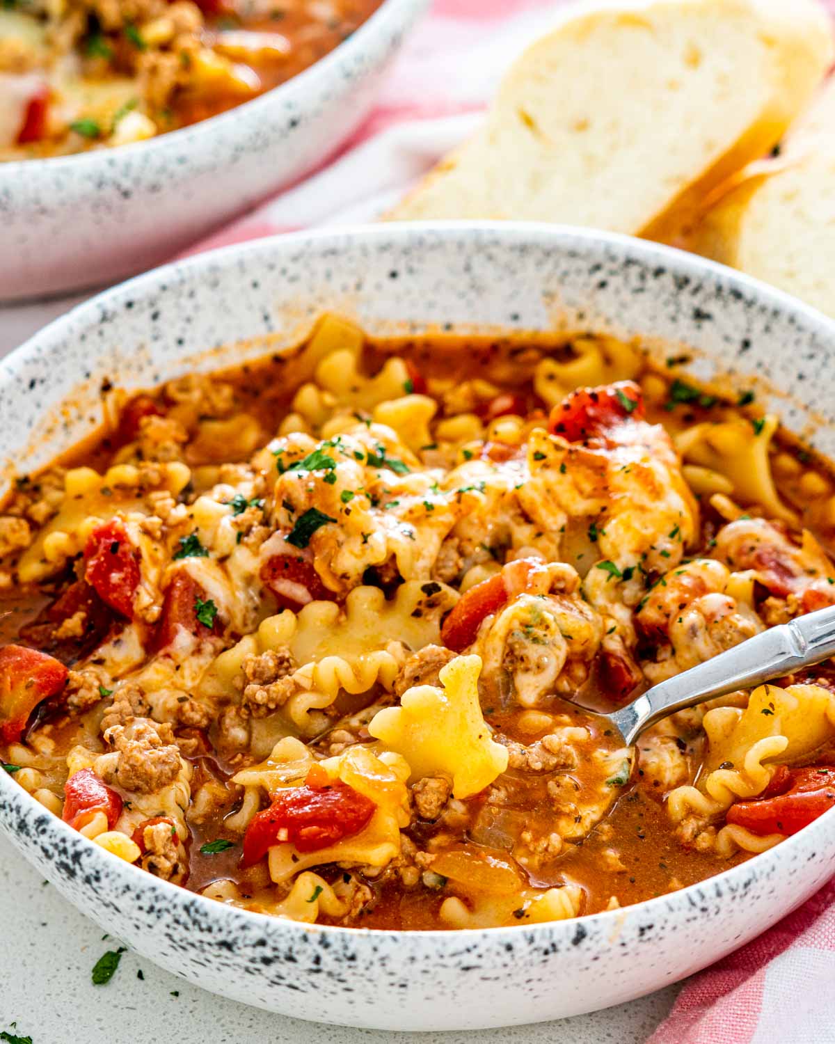 closeup of lasagna soup in a bowl with a spoon inside.