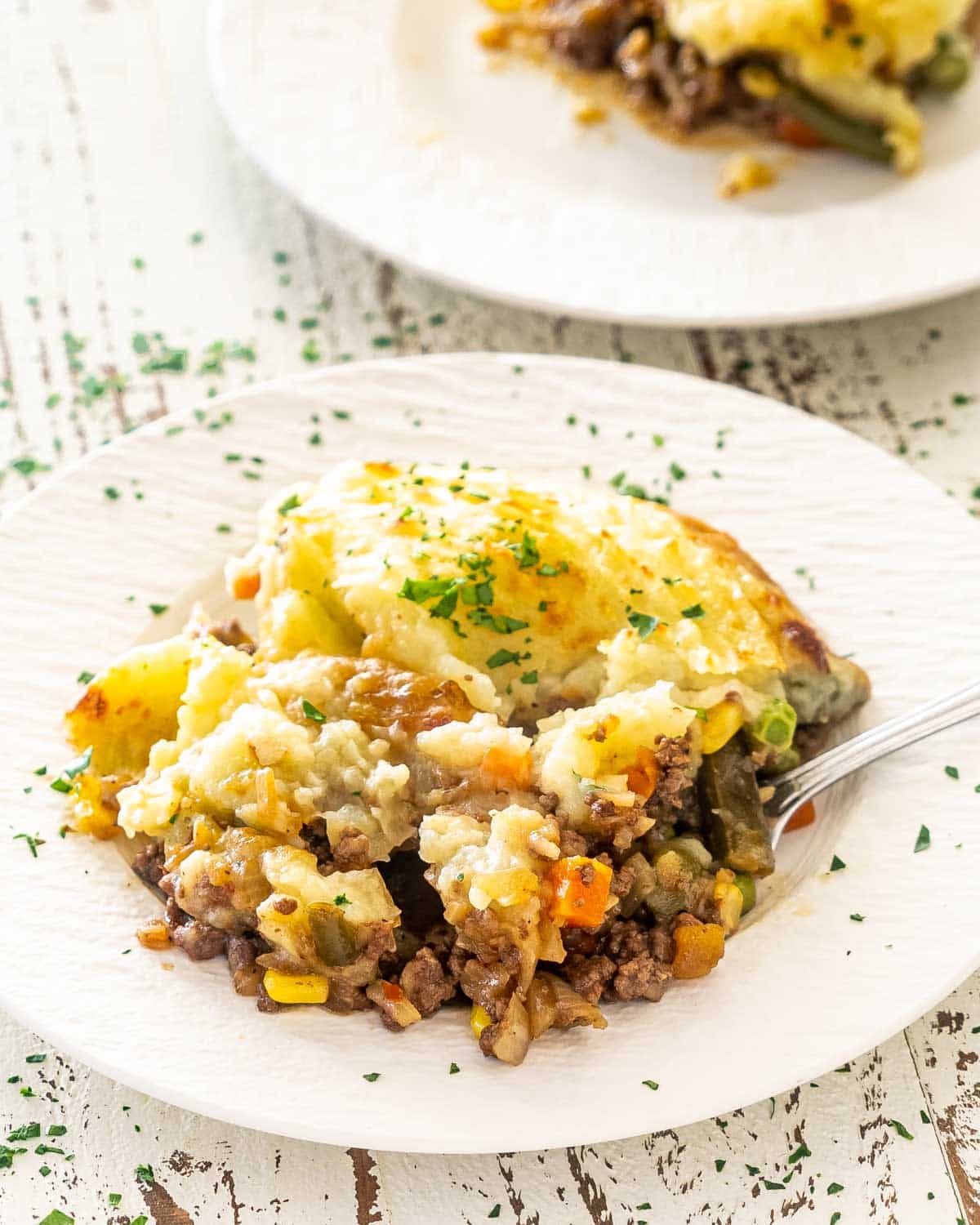 a serving of shepherd's pie in a white plate with a fork.
