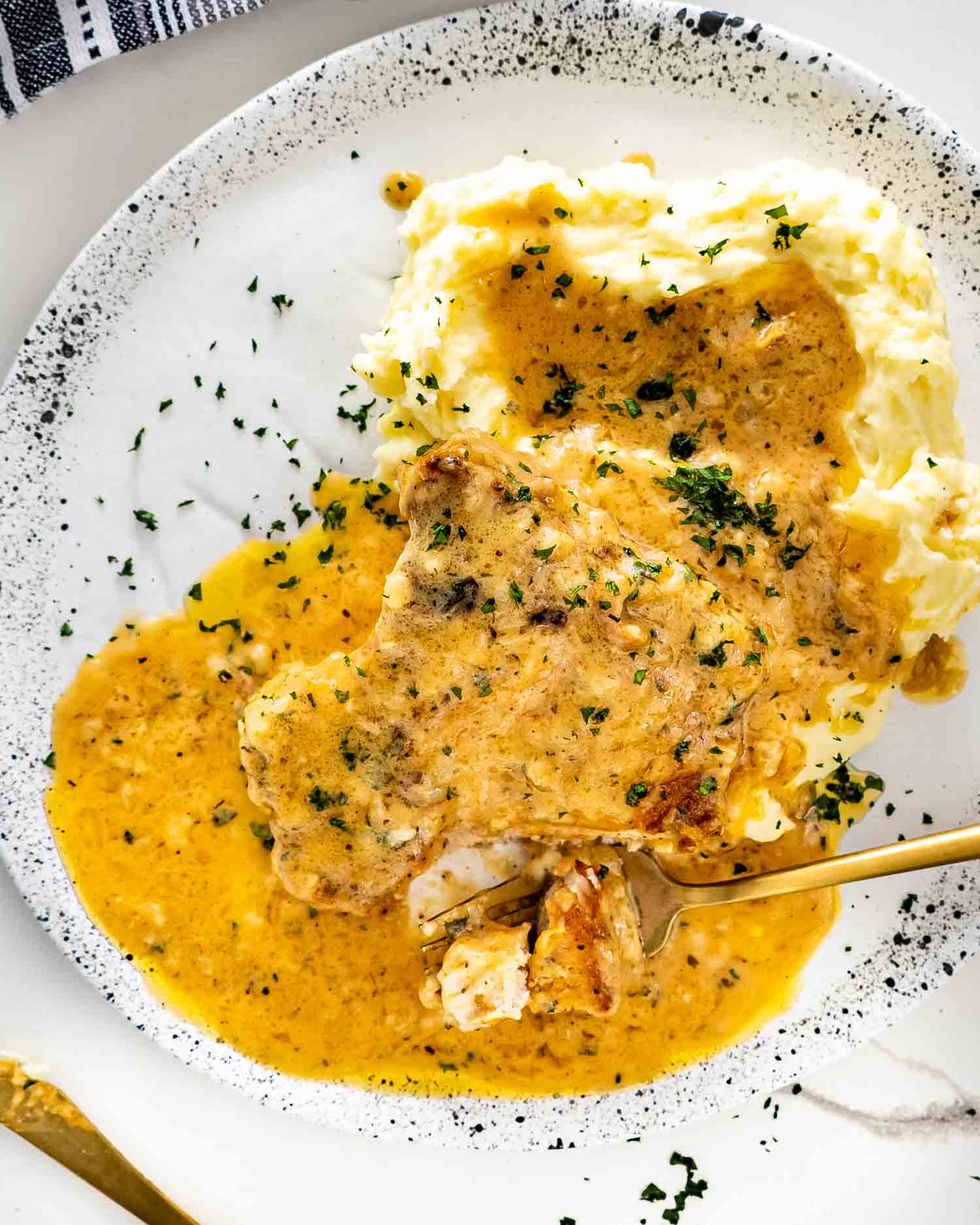 a smothered pork chop over a bed of mashed potatoes.